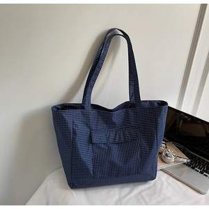 Detail of navy blue checkered tote bag with front flap pocket and sturdy shoulder straps