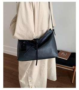 Détail du sac cabas tissé noir porté avec un trench-coat classique beige chic