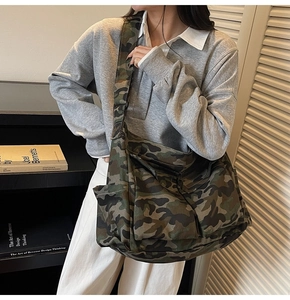 Detail of a large camouflage canvas tote bag featuring side pockets and adjustable strap