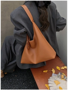 Detail of caramel brown underarm bag with lychee texture carried over shoulder