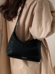 Suede and leather black shoulder bag for women shown from a side view on a model