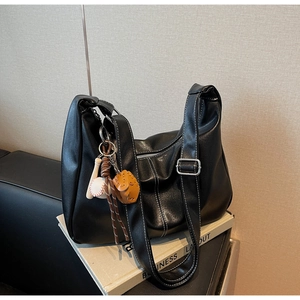 Detail of black synthetic leather tote with white contrast stitching and baseball charms
