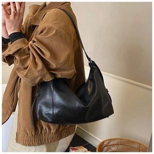 Close-up of black retro tote bag with oil wax leather texture and pleated seam detail