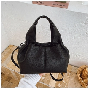 Détail d'un sac hobo noir à texture litchi avec boucles argentées en scène minimaliste
