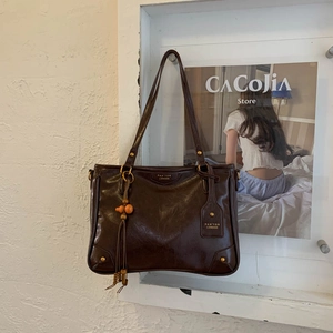 Close-up of deep brown vintage tote bag featuring a decorative tassel and wood bead charm