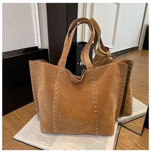 Détail du sac cabas en daim marron avec rivets métalliques argentés verticaux