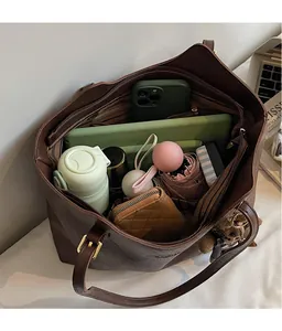 Macro detail of spacious brown tote bag interior holding a tablet, phone, and daily essentials
