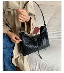 Détail de la texture tressée noire et du design hobo sur un grand sac cabas porté épaule