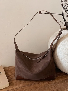 Retro brown suede shoulder tote bag with adjustable strap on a minimalist wooden table
