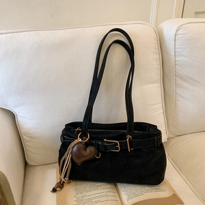 Close-up of black suede shoulder bag with gold buckle and brown heart charm detail