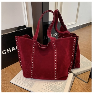 Détail d'un grand sac cabas en daim bordeaux avec rivets argentés et texture cuir