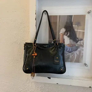 Close-up of black retro leather tote with gold rivets and bohemian tassel detail