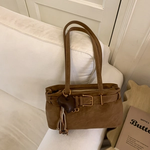 Detailed view of brown vintage leather bag with gold buckle, heart charm and tassel