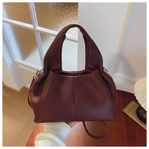 Gros plan détaillé d'un sac seau bordeaux en cuir grainé avec poignée et bandoulière