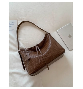 Détail du sac cabas tressé marron foncé avec tablette et magazine sur tissu doux