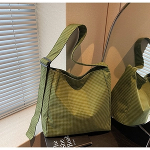 Detail of green plaid oxford shoulder bag showing wide strap and adjustable buckle closure