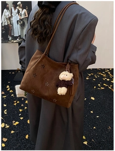 Détail du sac fourre-tout en daim marron avec fleurs découpées au laser et porte-clé ours