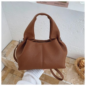 Détail d'un sac seau marron avec motif litchi, poignée élégante et finitions en métal argenté