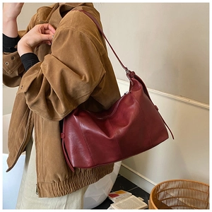 Detailed side view of deep red leather tote bag showing fine stitching and strap texture