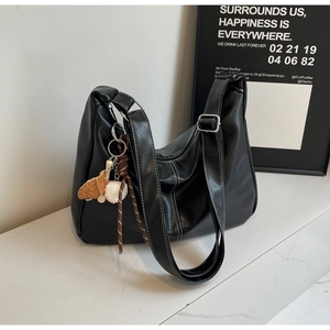 Detail of black faux leather tote with white contrast stitching and baseball charm