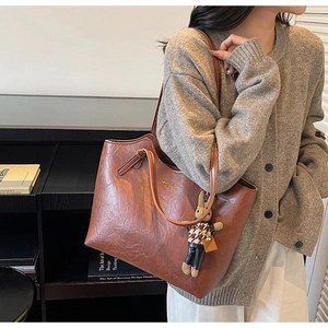 Detail of vintage brown leather tote bag with fashion gold foil text and plush rabbit charm