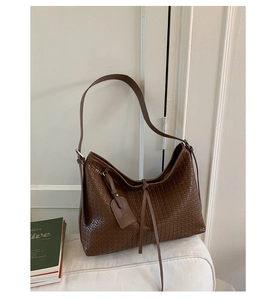 Détail de la texture tressée marron foncé d'un sac hobo polyvalent avec garniture argent