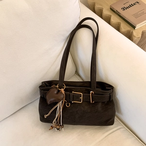 Detail of dark brown suede shoulder bag with gold buckle and heart-shaped tassel charm