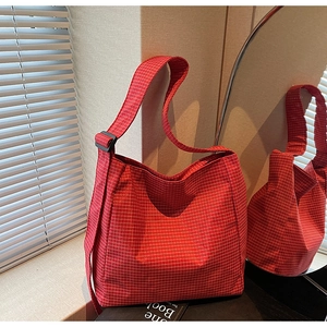 Detail of red checkered canvas tote with adjustable strap and black buckle closure