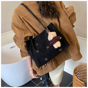 Détail du sac cabas noir avec motifs de fleurs découpées et breloque ours en peluche