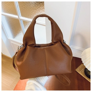 Détail de la texture cuir litchi marron et coutures verticales sur le sac seau