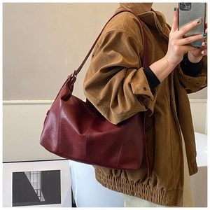 Burgundy faux leather tote bag with adjustable strap shown on model in a mirror selfie