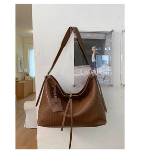 Détail d'un sac à main marron foncé à texture tissée avec finition en cuir mat