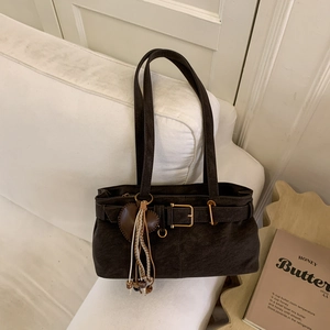 Close-up of vintage brown leather underarm bag with heart pendant and metallic buckle detail