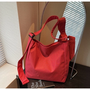 Detail view of red checkered canvas tote with adjustable strap in casual interior setting