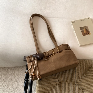 Detailed close-up of brown suede shoulder bag with heart pendant and fringe tassels