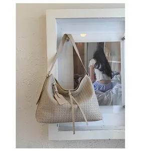 Détail du sac hobo tissé beige montrant la texture croisée et la bandoulière