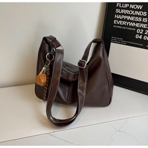 Detail of dark brown leather tote featuring white contrast stitching and adjustable buckle