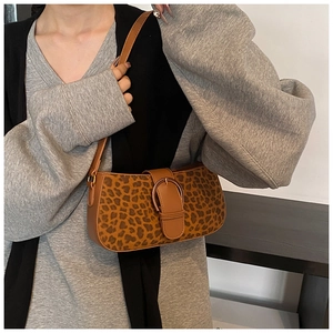 Detailed close-up of leopard print shoulder bag with brown leather strap and metal buckle