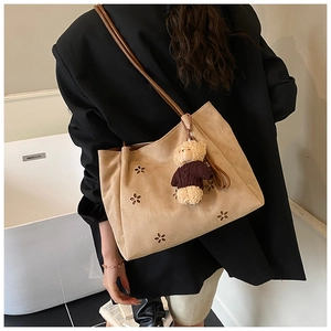 Detail of beige shoulder bag with laser-cut floral patterns and a cute bear charm