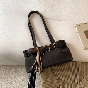 Close-up of retro brown shoulder bag with metal belt buckle and woven fringe detail