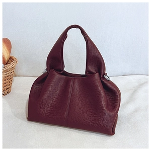 Vue détaillée du sac seau bordeaux en cuir litchi avec anneau en D et texture souple