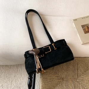 Detail of black suede shoulder bag with gold hardware and heart tassel decoration
