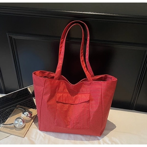 Macro detail of red and white plaid tote bag featuring a front pocket and slender straps