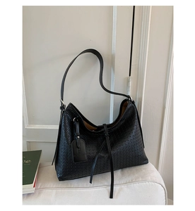 Gros plan sur la texture tissée noire et la bandoulière en cuir de ce sac fourre-tout