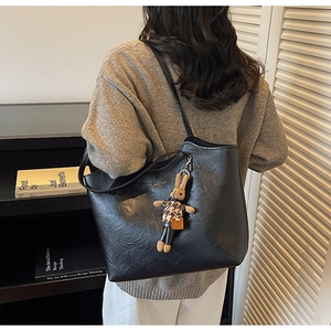 Detail of black faux leather tote bag with vintage texture and cute bunny keychain
