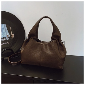 Détail de la texture cuir grainé marron foncé et des coutures du sac seau