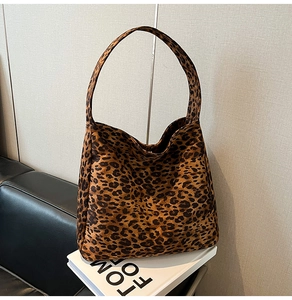 Détail du sac cabas imprimé léopard avec larges anses sur un fond décoratif minimaliste