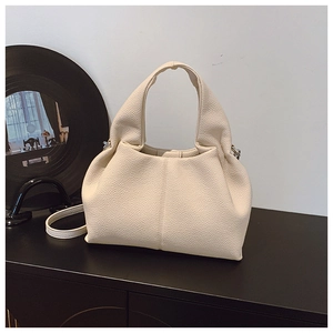 Vue détaillée du sac seau crème montrant le cuir à texture lychee et la poignée large