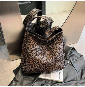 Détail du sac cabas à imprimé léopard posé sur une veste en cuir noir pour un look citadin