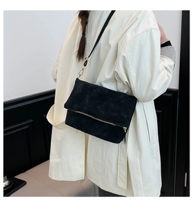 Detail view of black matte suede crossbody bag with gold zipper and minimalist strap